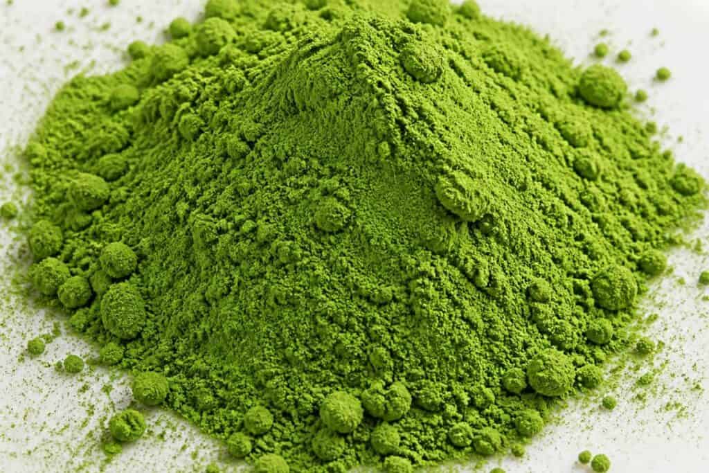 What Is Matcha? A Guide to the Tea, Taste, Benefits and Preparation 7 مسحوق ماتشا أخضر مكوّم على طبق خزفي أبيض